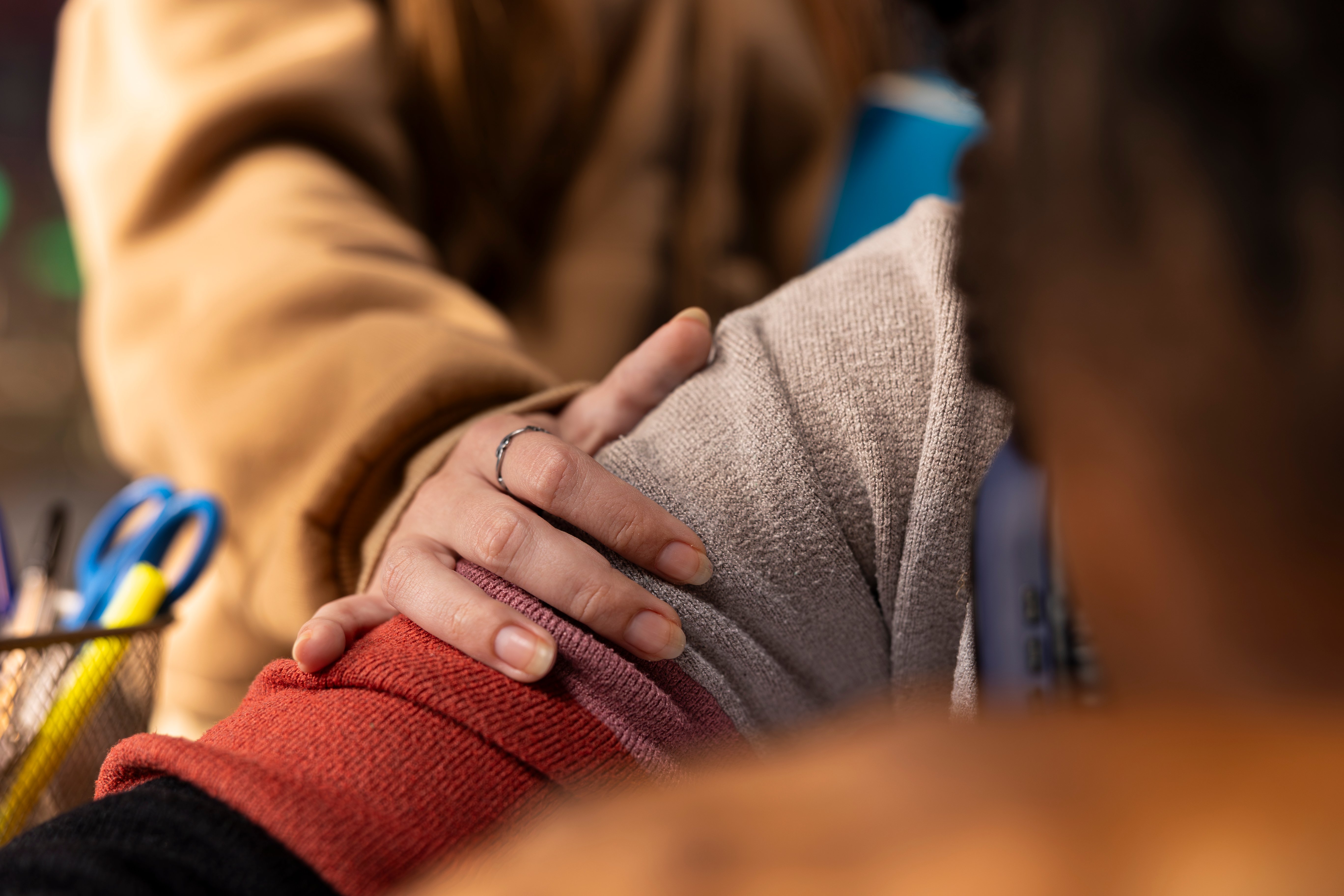 A woman's hand resting on a person's shoulder